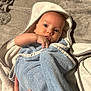 baby, towel, hooded_towel, infant, blanket, hand, soft_texture, blue, white, skin, face, eyes, person, newborn, cozy, lying_down, indoor, curious, wrapped, comfort