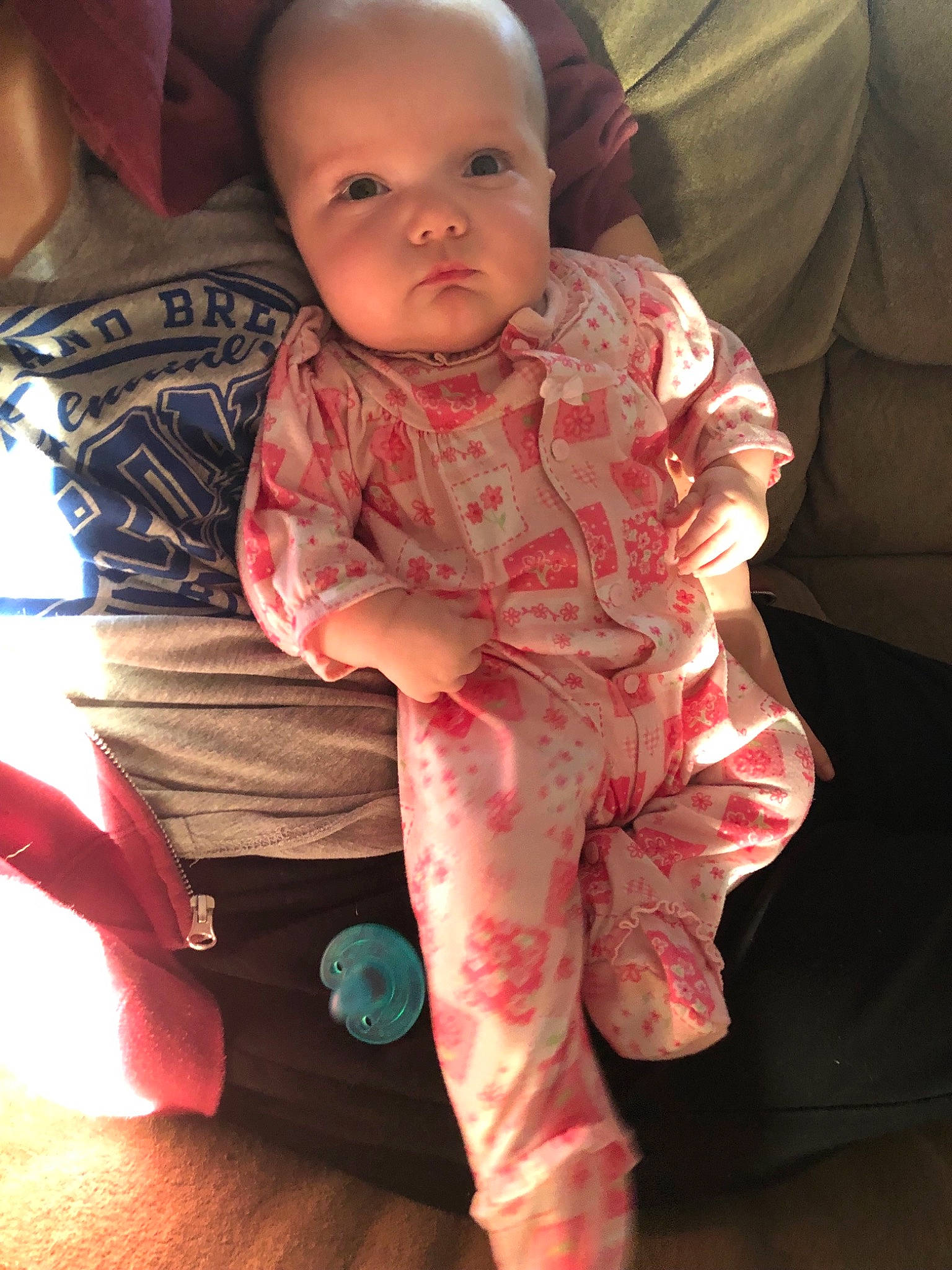 Emmaline is registered to the contest to win money with this photo: arm, baby, cheek, child, eye, face, head, joint, leg, pajamas, person, pink, sitting, skin, sleeve, smile, standing, toddler, vacation