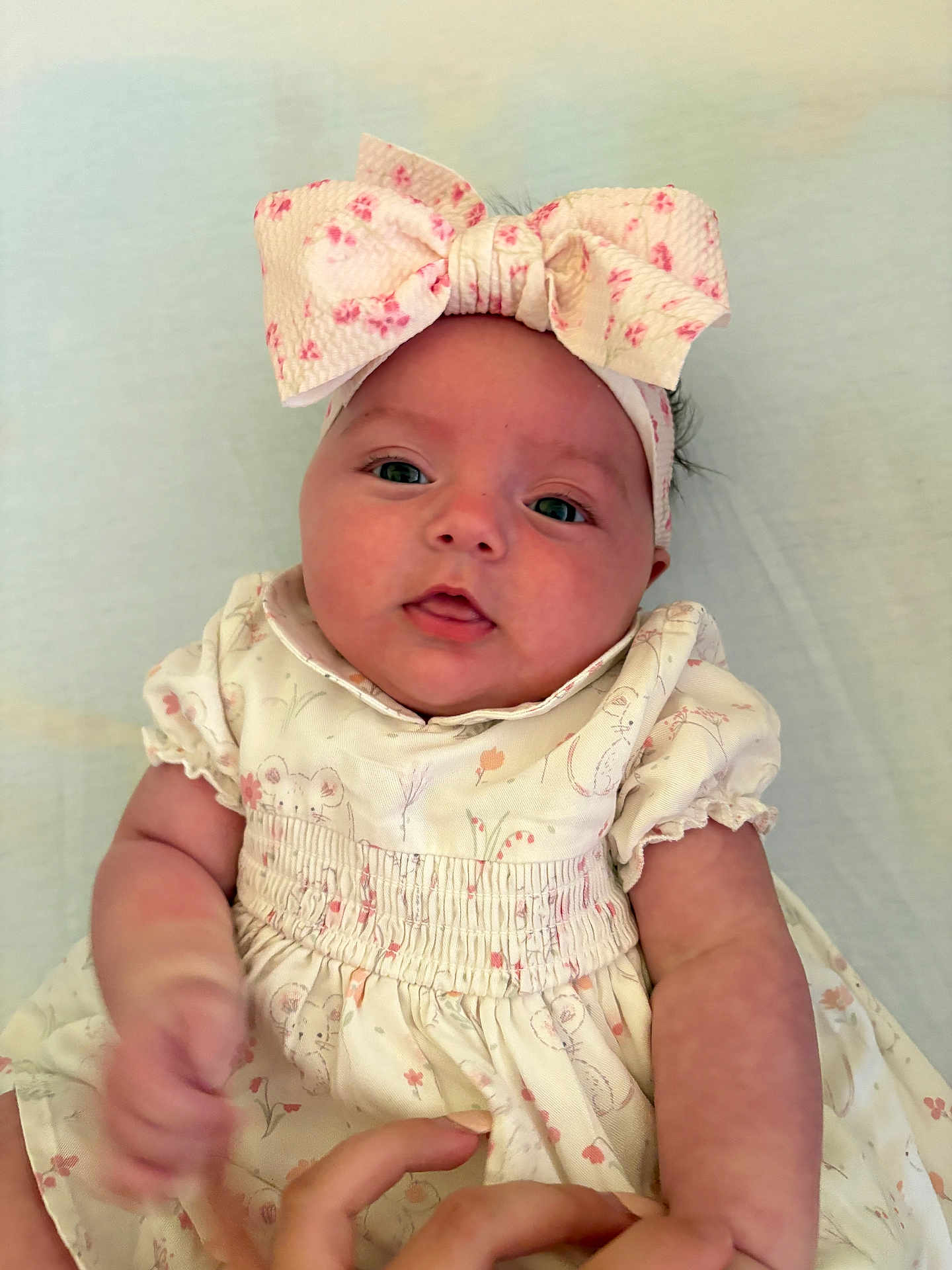 Pebble is registered to the contest to win money with this photo: baby, infant, headband, dress, floral, cute, child, portrait, skin, hand, lying_down, soft_surface, apparel, pink, white, closeup, adorable, young, person, expression