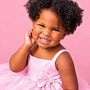 Karmen is registered to the contest to win money with this photo: child, toddler, portrait, smiling, happy, curly_hair, pink_dress, formalwear, bow, tutu, sitting, studio, pink_background, fashion, cute, african_american, face, teeth, joyful, photography