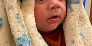 Hayes is registered to the contest to win money with this photo: baby, blanket, face, child, infant, curious, wide_eyes, soft_texture, warm, indoor, cute, closeup, portrait, cozy, wrapped, expression, head, human, newborn, snug