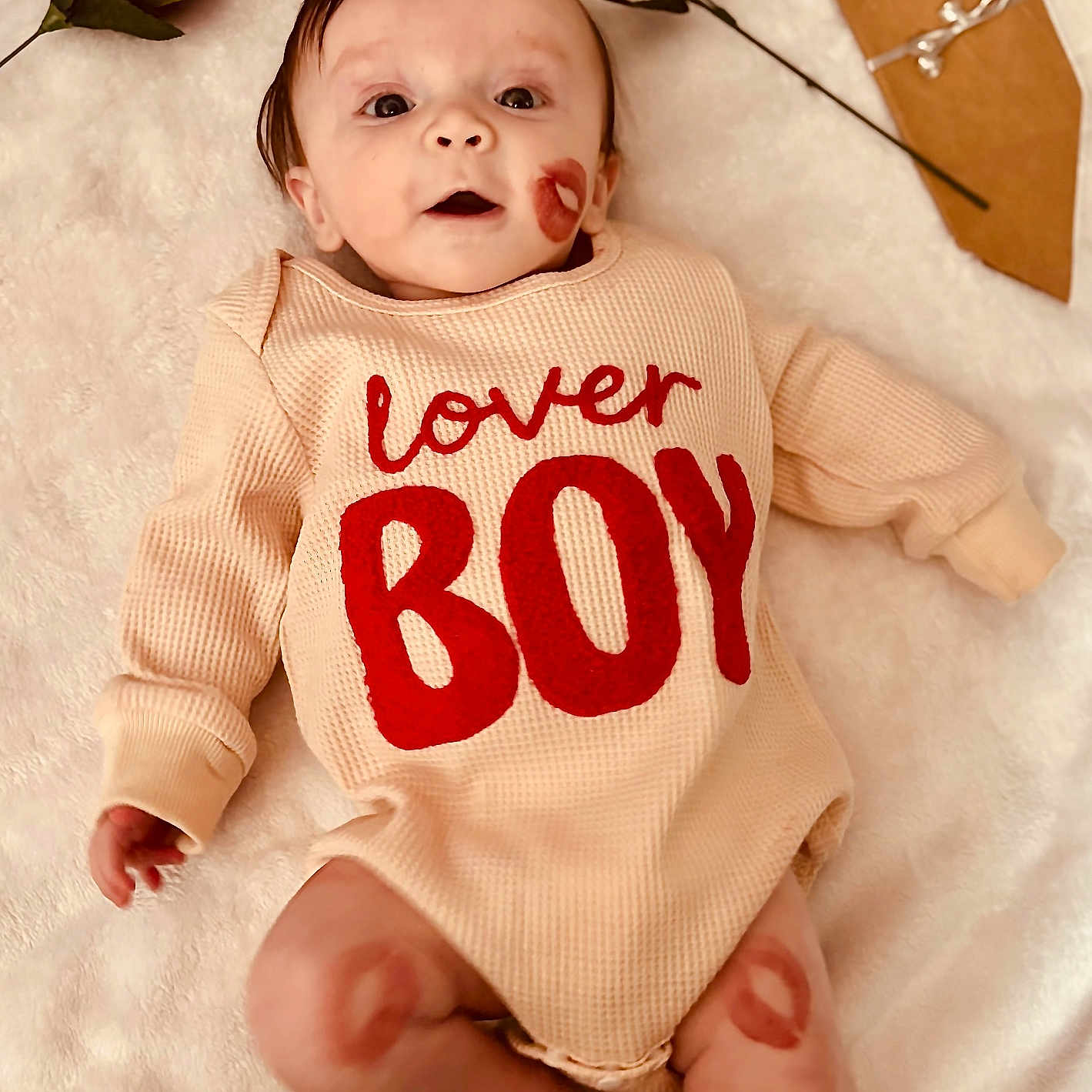 Ryden is registered to the contest to win money with this photo: baby, bouquet, child, cozy, cute, gift_wrap, hands, indoor, infant, kiss_mark, legs, lipstick_mark, lying_down, onesie, open_mouth, portrait, red_text, rose, soft_blanket, valentine_theme