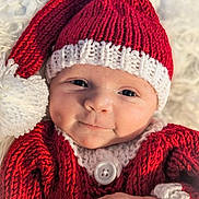 Ryden is registered to the contest to win money with this photo: baby, infant, newborn, knit_hat, santa_hat, red_hat, white_trim, blanket, cozy, button, hand, portrait, closeup, blue_eyes, smile, cute, holiday, knitwear, soft_texture, skin