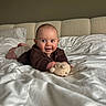 baby, infant, smiling, bed, blanket, teddy_bear, toy, indoor, cute, child, happy, face, clothing, lying_down, pillow, cozy, home, portrait, young, comfort