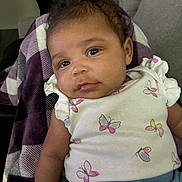 Journee joined the competition — help win amazing prizes! baby, infant, child, face, eyes, smile, clothing, butterfly_pattern, blanket, purple, white, blue_pants, curly_hair, skin, arm, couch, indoor, portrait, cozy, person