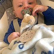Lyvio participe au concours pour gagner de l'argent avec cette photo : baby, infant, pacifier, blanket, stuffed_animal, baby_seat, seat_strap, blue_clothing, hand, face, eyes, close_up, portrait, bedding, cozy, plush, pacifier_clip, awake, nursery_item, soft_toy