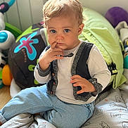 Gabriel participe au concours pour gagner de l'argent avec cette photo : baby, blanket, child, clothing, comfort, curly_hair, cushion, cute, expression, face, floor, hand, indoor, jeans, long_sleeve_shirt, playtime, portrait, toddler, toy, vest