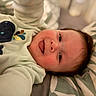 baby, baby_garment, child, closeup, clothing, cozy, cute, expression, face, happy, indoors, infant, lying_down, pattern, pillow, portrait, smiling, soft_light, tongue_out, whale_design
