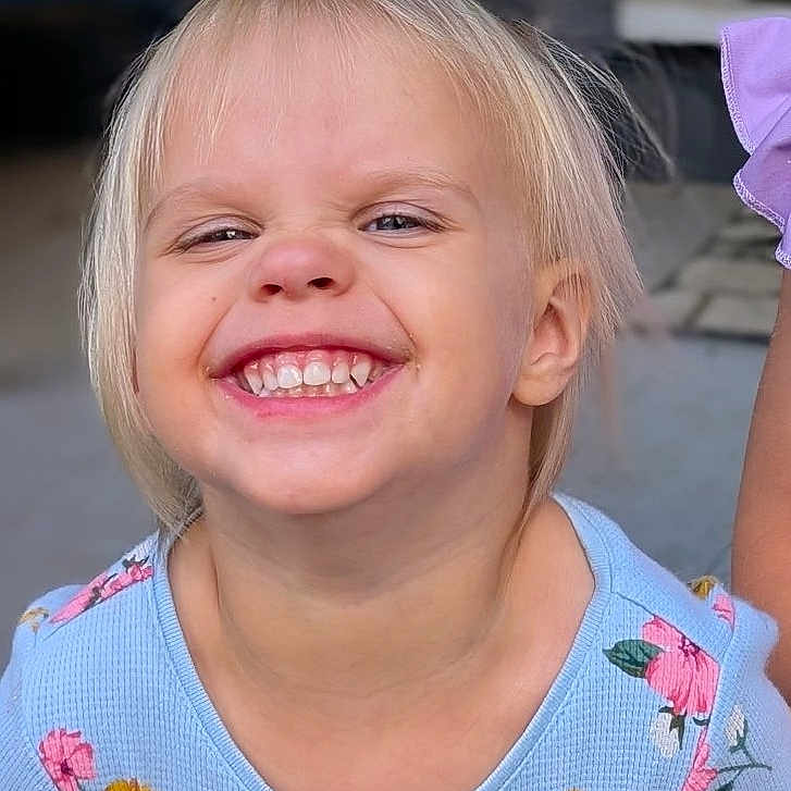 Gwenevere joined the competition — help win amazing prizes! blond_hair, blue_clothing, child, closeup, cute, expression, face, floral_pattern, hair, happy, head, joy, outdoor, person, portrait, skin, smile, teeth, toddler, young