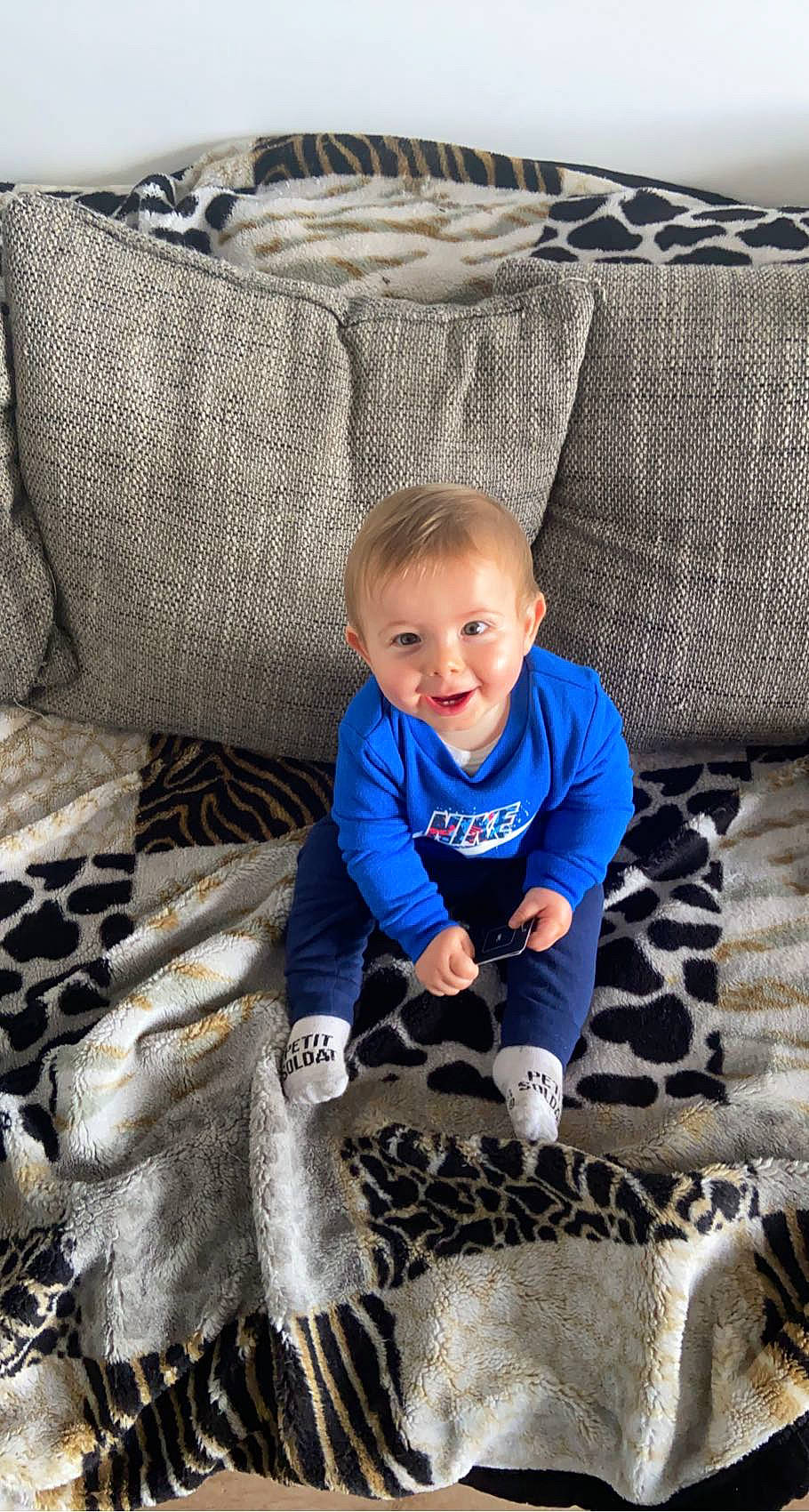 Mayron a rejoint le concours — aidez-le/la à gagner de superbes lots ! baby, baby_toddler_clothing, child, comfort, couch, electric_blue, flooring, grass, grey, happy, linens, pattern, person, room, sitting, sleeve, smile, t_shirt, textile, toddler