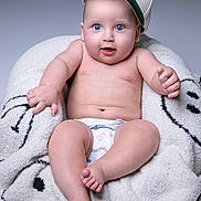 Ethan is registered to the contest to win money with this photo: baby, blue_eyes, cap, diaper, blanket, fluffy, cute, infant, smiling, sitting, hand, foot, skin, expression, portrait, indoor, child, young, hat, comfortable