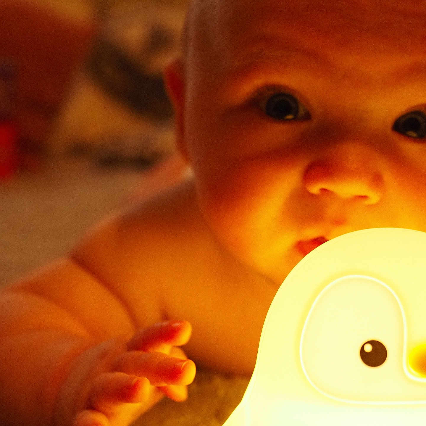 Hugo is registered to the contest to win money with this photo: baby, baby_toy, carpet, child, closeup, curious, cute, expression, face, hand, indoor, infant, light, night_light, penguin, portrait, skin, soft_texture, toy, warm_light