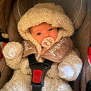 Hazel joined the competition — help win amazing prizes! baby, pacifier, car_seat, snowsuit, hood, fluffy, warm_clothing, infant, child, seatbelt, cute, portrait, indoor, newborn, soft_texture, winter_wear, bundle_up, face, safety_strap, looking_at_camera