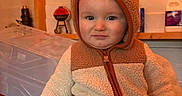 Jaxson joined the competition — help win amazing prizes! adult_hand, baby, background, blue_eyes, child, cozy, curious, face, fleece, hand, hooded_jacket, household_items, indoor, person, plastic_container, portrait, shelf, toddler, warm_clothing, wooden_beams