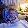 Jaxson joined the competition — help win amazing prizes! baby, bottle, child, clothing, curtains, face, furniture, hair, hand, high_chair, indoor, lamp, living_room, person, room, seat, smiling, table, toddler, window