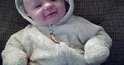 Noah is registered to the contest to win money with this photo: baby, child, infant, onesie, hood, couch, smile, fuzzy_clothing, seated, indoors, cute, warm_clothing, face, headwear, plush, cozy, person, young, small, comfort