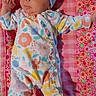 Emma joined the competition — help win amazing prizes! baby, infant, child, onesie, floral_pattern, hat, bow, blanket, pink, colorful, cute, lying_down, portrait, baby_clothes, newborn, pattern, smile, indoors, person, headwear