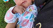 Emma is registered to the contest to win money with this photo: arm, baby, blue_bow, casual_clothing, child, closeup, colorful, floral_pattern, grass, hand, headband, holding, infant, nature, onesie, outdoor, peaceful, person, sleeping, toy