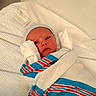 Sebastian is registered to the contest to win money with this photo: newborn, baby, hospital, blanket, striped_cap, bed, white, wrapped, infant, cute, portrait, lying_down, swaddled, person, child, fresh, small, face, sleepwear, resting