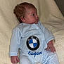 baby, infant, onesie, blue_clothing, bmw_logo, embroidered_text, blanket, soft_texture, side_profile, human, child, cute, resting, indoors, portrait, small_hands, footed_pajamas, comfortable, young, cozy