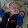 baby, sleeping, infant, portrait, indoors, blanket, bed, blue_clothing, black_clothing, fists, peaceful, resting, cozy, close_up, face, closed_eyes, baby_clothing, zipper, nike_logo, timestamp
