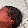 newborn, baby, infant, curly_hair, head, ear, skin, blanket, pattern, fabric, clothing_tag, closeup, sleeping, child, young, soft_skin, resting, indoors, portrait, human