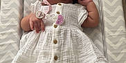 Arie-Rae is registered to the contest to win money with this photo: baby, infant, pacifier, white_dress, socks, changing_pad, chevron_pattern, curly_hair, indoors, couch, soft_lighting, child, newborn, cute, relaxing, portrait, sleepwear, comfort, skin, hand