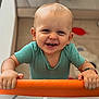 baby, child, smiling, playpen, onesie, bracelet, indoor, happy, cute, holding, face, teeth, person, infant, looking_at_camera, short_hair, home, toy, floor, colorful