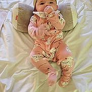Eliora joined the competition — help win amazing prizes! baby, infant, onesie, pink_clothing, cat_print, bed, pillow, plush, hand_in_mouth, cute, child, soft, sleepwear, head_support, lying_down, indoor, person, young_child, cozy, resting