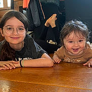Léo participe au concours pour gagner de l'argent avec cette photo : child, baby, glasses, smile, indoor, wooden_floor, sibling, happy, casual_clothing, long_hair, short_hair, portrait, person, floor, candid, home, natural_light, cute, family, relaxed