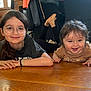 child, baby, glasses, smile, indoor, wooden_floor, sibling, happy, casual_clothing, long_hair, short_hair, portrait, person, floor, candid, home, natural_light, cute, family, relaxed