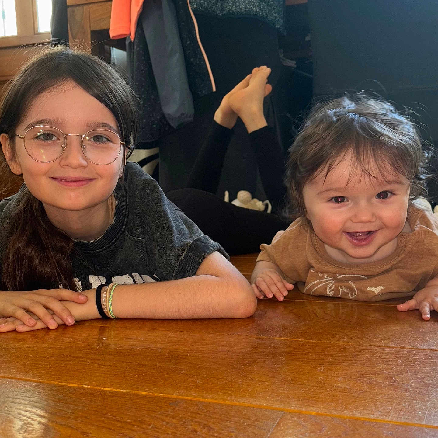 Léo participe au concours pour gagner de l'argent avec cette photo : baby, candid, casual_clothing, child, cute, family, floor, glasses, happy, home, indoor, long_hair, natural_light, person, portrait, relaxed, short_hair, sibling, smile, wooden_floor