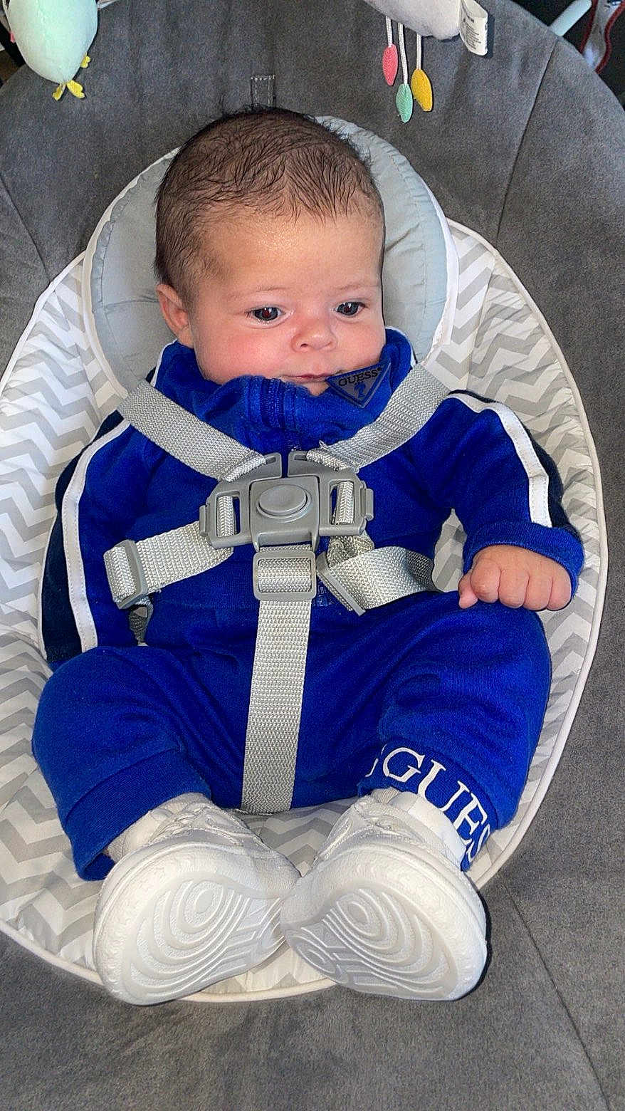 Kayron a rejoint le concours — aidez-le/la à gagner de superbes lots ! baby, infant, blue_outfit, white_sneakers, baby_seat, straps, zigzag_pattern, curly_hair, indoor, cute, child, seated, comfortable, clothing, footwear, face, expression, looking_down, safety_harness, soft_fabric