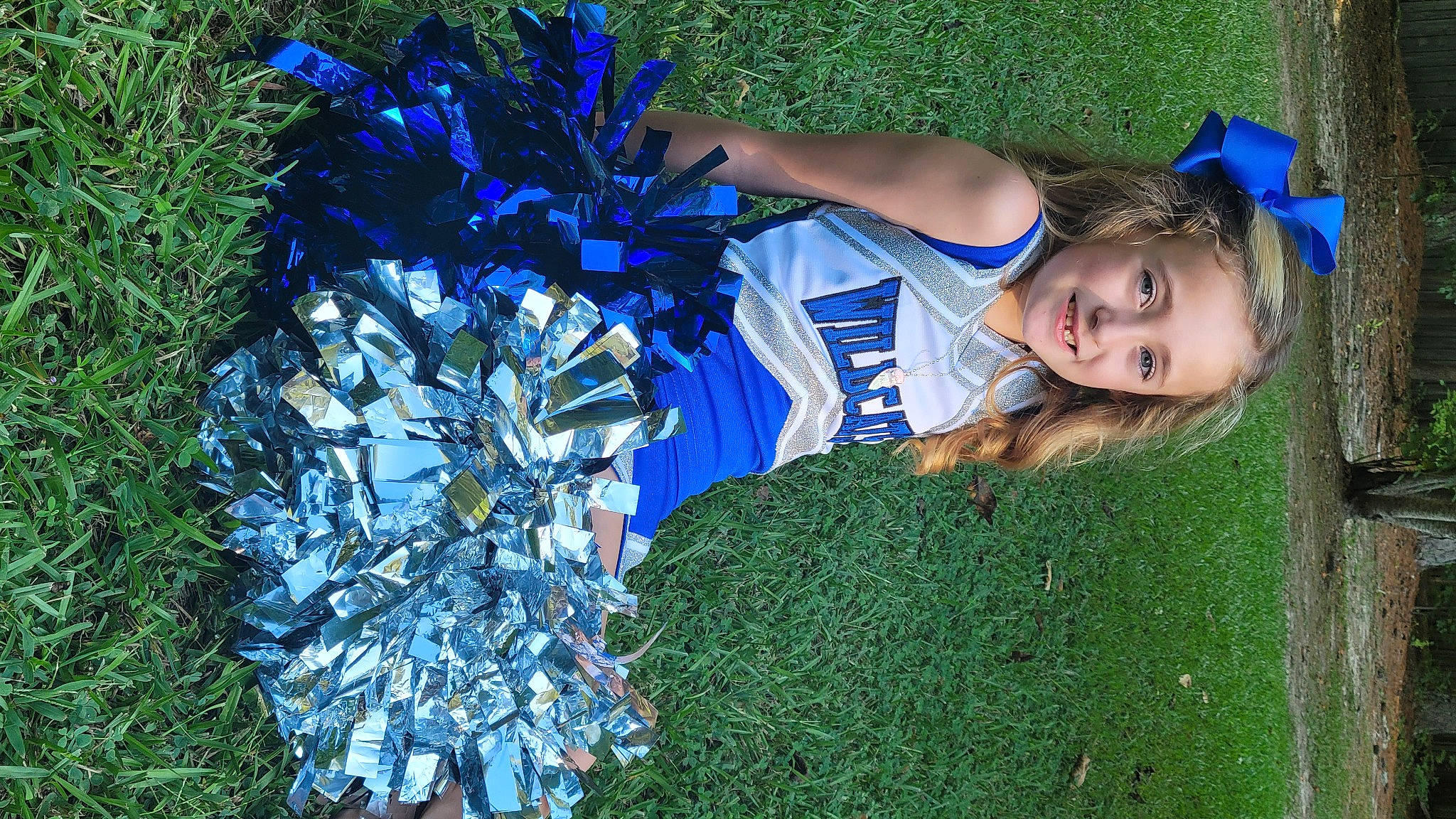Brielle is registered to the contest to win money with this photo: blue, cheerleading_uniform, electric_blue, event, fashion_accessory, fun, glove, grass, grassland, happy, headpiece, human_leg, joy, people_in_nature, person, plant, recreation, shrub, team_sport, toddler