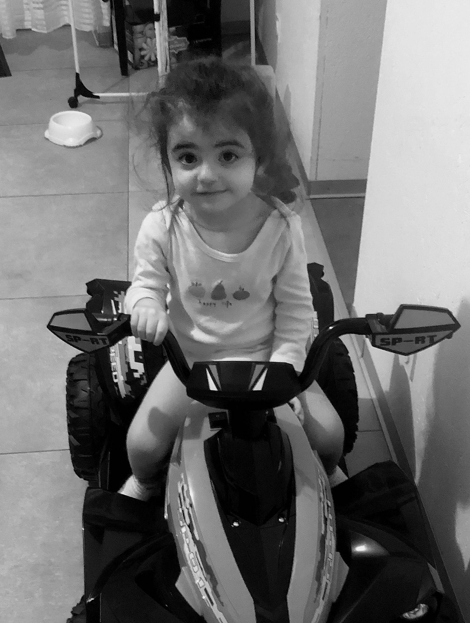 Chloé a rejoint le concours — aidez-le/la à gagner de superbes lots ! automotive_lighting, automotive_tire, black, black_and_white, child, fender, fun, hair, joy, monochrome, monochrome_photography, person, photograph, rim, sitting, smile, standing, style, tire, toddler