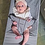 baby, baby_bouncer, babybjorn, barefoot, child, clothing, cute, expression, face, floor, gray, headband, indoor, infant, kitchen, looking, person, relaxed, seat, soft_lighting
