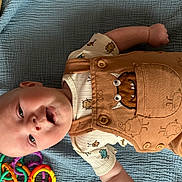Rune joined the competition — help win amazing prizes! baby, infant, smiling, lying_down, overalls, monster_design, shirt, blue_blanket, toy, colorful, plastic_rings, cute, child, happy, indoors, clothing, portrait, one_person, casual, playful