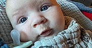 Rune is registered to the contest to win money with this photo: baby, blanket, blue_eyes, child, clock, close_up, cloth, couch, cute, expression, face, indoor, infant, living_room, newborn, pacifier, person, portrait, soft_lighting, wrapped
