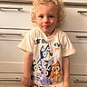 child, toddler, curly_hair, smile, tshirt, cartoon, indoor, kitchen, cabinet, drawer, blond, person, cute, standing, young, portrait, casual_clothing, happy, light_skin, funny