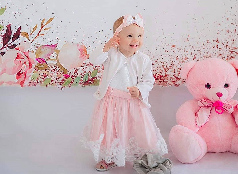 Maria participe au concours pour gagner de l'argent avec cette photo : baby, baby_toddler_clothing, child, event, flower, happy, headgear, headwear, joy, magenta, pattern, peach, person, petal, pink, plant, product, skin, smile, textile