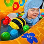 Manoa a rejoint le concours — aidez-le/la à gagner de superbes lots ! toddler, child, inflatable_pool, water, toy, bee, ball, blue_hat, striped_clothing, summer, play, happy, smile, outdoor, colorful, plastic, fun, cute, splash, bright