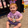 Ariah joined the competition — help win amazing prizes! toddler, child, smiling, purple_bow, purple_clothing, comb, carpet, crib, toy, nursery, earrings, sitting, happy, indoor, person, hair_accessory, playful, cute, floor, room