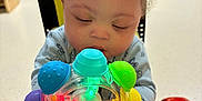 Jahlil joined the competition — help win amazing prizes! baby, blue, child, colorful, curly_hair, face, focus, green, hands, indoor, infant, light, person, plastic, playroom, red, sitting, table, toy, yellow