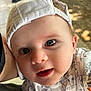 baby, child, face, cap, white_cap, onesie, patterned_clothing, curious, wide_eyes, close_up, portrait, infant, cute, adorable, expression, skin, headwear, person, young_child, indoors