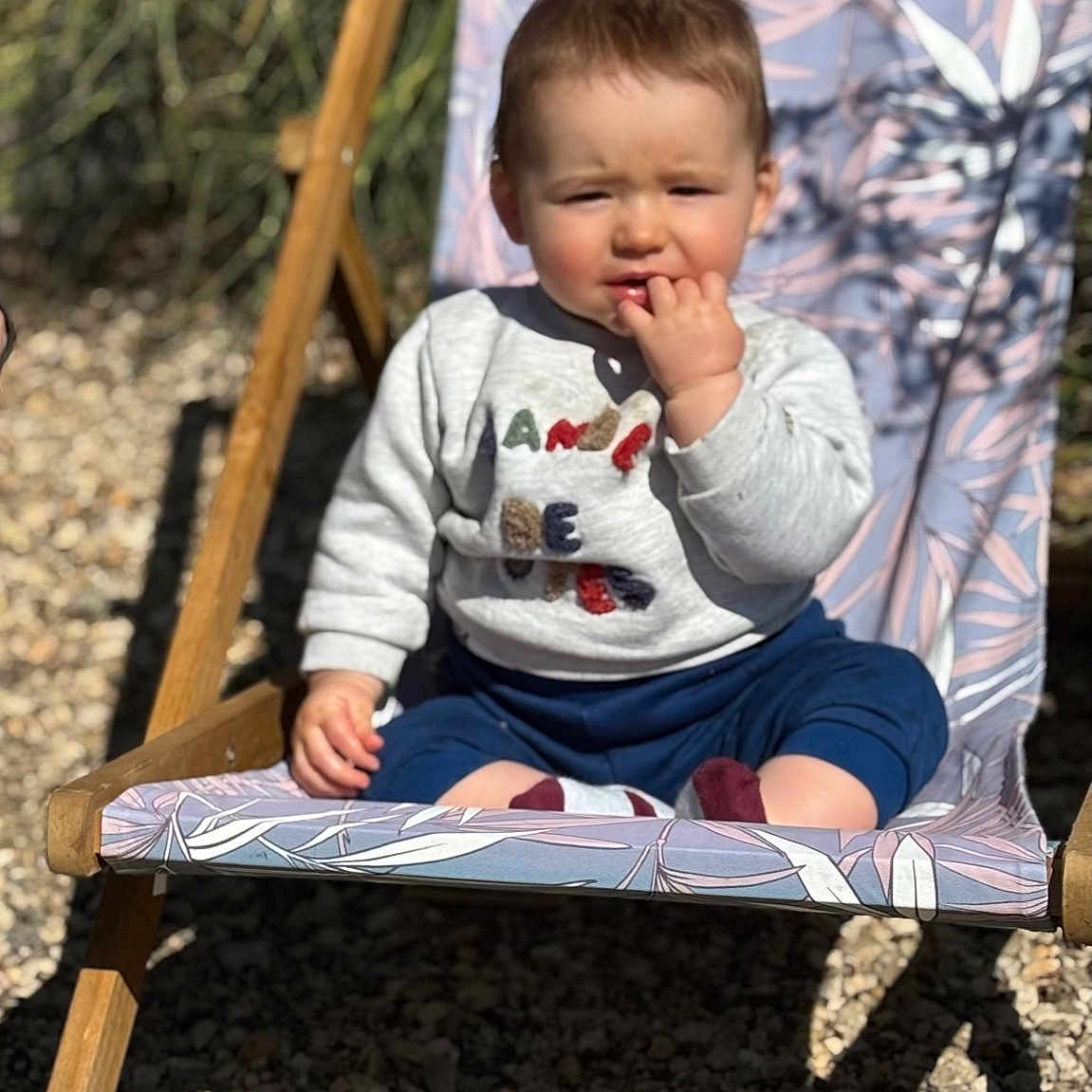 Liam a rejoint le concours — aidez-le/la à gagner de superbes lots ! baby, chair, clothing, face, furniture, grass, head, nature, outdoors, pants, person, photography, plant, portrait, rock, sitting, soil, summer, t_shirt, wood