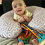 baby, infant, smiling, boppy_pillow, leopard_print, toy_keys, colorful_toys, sitting, living_room, couch, blanket, hands, feet, portrait, cute, happy, indoor, face, closeup, playtime