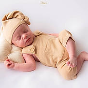 Elio participe au concours pour gagner de l'argent avec cette photo : newborn, baby, sleeping, infant, pillow, knotted_hat, beige_outfit, soft_fabric, peaceful, portrait, closeup, skin, headwear, resting, cute, child, studio, minimalist, background, pose