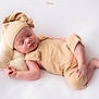 newborn, baby, sleeping, infant, pillow, knotted_hat, beige_outfit, soft_fabric, peaceful, portrait, closeup, skin, headwear, resting, cute, child, studio, minimalist, background, pose