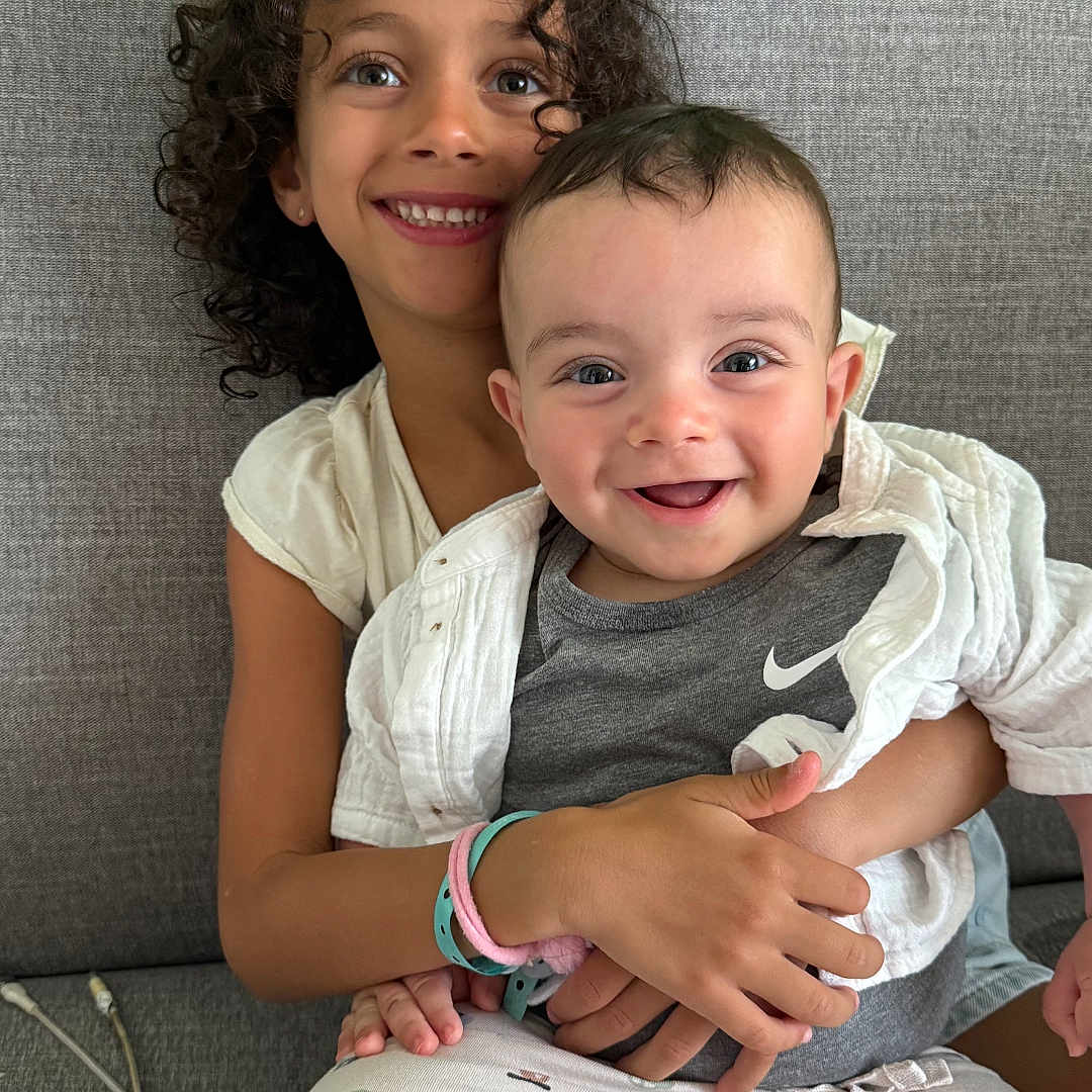 Adam participe au concours pour gagner de l'argent avec cette photo : baby, baby_clothes, bracelet, child, clothing, couch, curly_hair, cute, family, gray_couch, green_wall, happy, hug, indoor, pajamas, person, portrait, sitting, smile, toddler