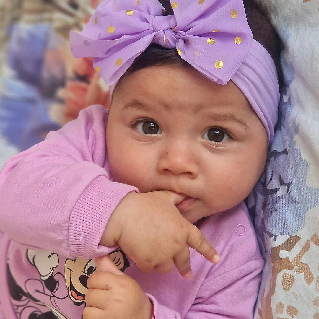 Klara participe au concours pour gagner de l'argent avec cette photo : baby, blanket, child, cute, expression, eyes, face, fingers, hand, headband, indoors, infant, lying_down, minnie_mouse, pattern, pink_clothing, portrait, purple_bow, sleeve, soft_light
